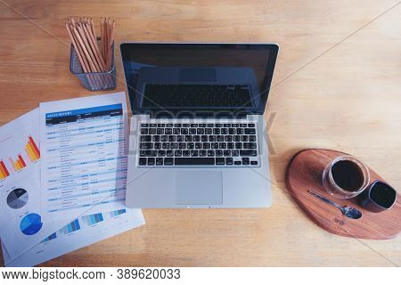 Office Laptop Business Financial Document Chart And Graph On Wooden Table With Coffee Cup. Flat Lay 