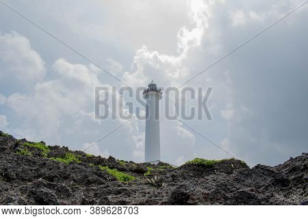 Cape Zanpa Lighthouse With Surrounding Volcanic Rock Formation And Silver Line Sky With Grey Clouds