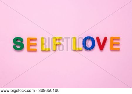 Self Love Text On Pink Paper Background Made From Colorful Plastic Letters. Multicolored Inscription