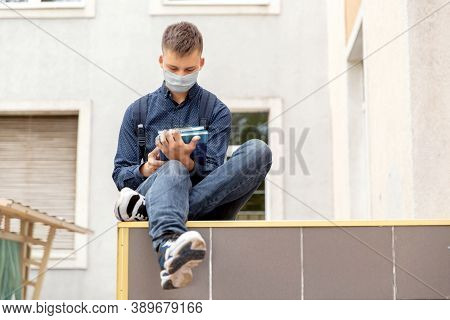 Teen Boy Sitting In The Background Of The School. He Reads Textbooks. His Face In A Medinah Face Mas