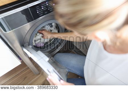 Woman Folds Clothes Into The Washing Machine. Home Help Service And Service Concept