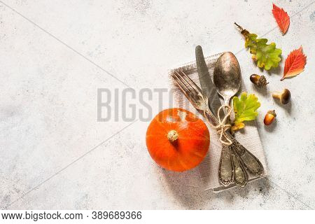 Fall Table Setting With Silverware, Pumpkin And Leaves At White Table. Top View With Copy Space.