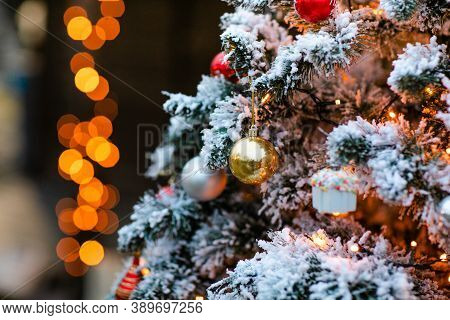 Fir Tree Decorated With Snow And Golden Glass Ball And Light Bulbs For Christmas And New Year Celebr