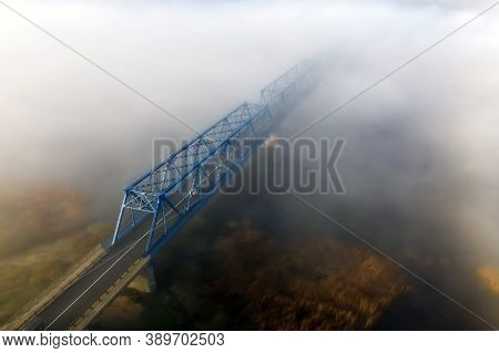View From Above On A Metal Bridge Over The River Lielupe Wrapped In Fog In The Autumn Morning. The F