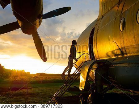 Yo Ungwoman Standing At Plane Ladder Going To Board, Outdoors, Airport. Old Soviet Military Airplane