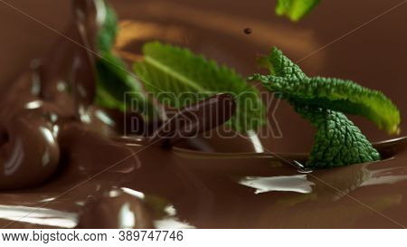 Detail of pouring hot chcocolate with mint leaves. Studio macro shot.