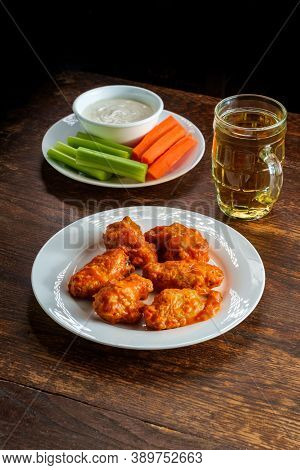 Bar Or Pub Food Spicy Buffalo Wings And Beer With Sliced Carrot Sticks Celery And Blue Cheese Dressi