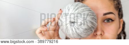 A Beautiful Young Girl Knitter Smiles And Holds Skeins Of Light Gray And White Yarn In Her Hands. Wo