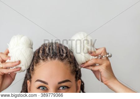 A Beautiful Young Girl Knitter Smiles And Holds Skeins Of White Yarn In Her Hands, Applying Them To 