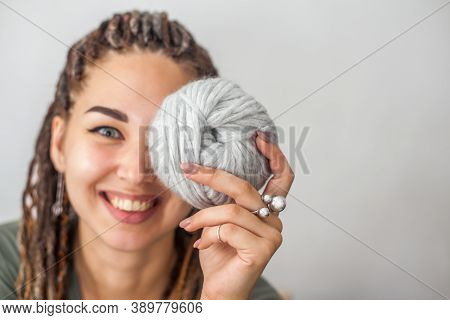 A Beautiful Young Girl Knitter Smiles And Holds Skeins Of Light Gray And White Yarn In Her Hands. Wo