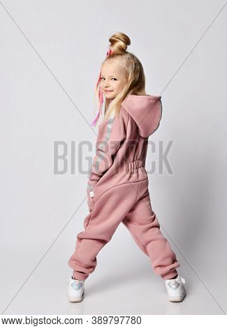 Sly Frolic Smiling Blonde Kid Girl With Braids In Stylish Pink Warm Jumpsuit With Hood And White Sne