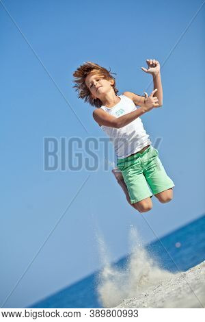 Child Playing On Ocean Beach. Kid Jumping In The Waves. Sea Vacation For Family With Kids. Little Bo