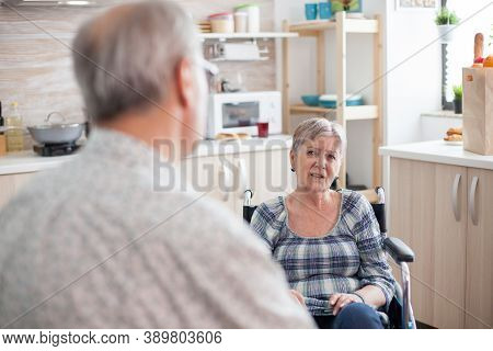 Gray Haired Man Chatting With Paralysed Wife. Retired Invalid Woman In Wheelchair Having A Conversat