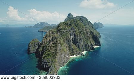 Hilly island at ocean gulf drone view. Green trees, plants at mountain rocks at paradise isle. Wonderful landscape of El Nido islet, Philippine, Visayas. Cinematic summer scenery aerial birds-eye shot