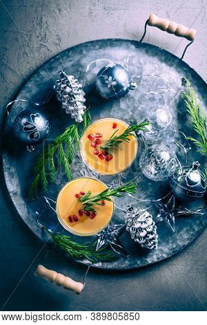 Traditional egg liqueur or eggnog with cinnamom, pomegranate and rosemary  with Christmas decoration