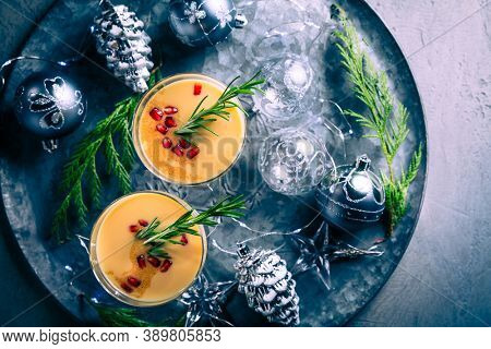 Traditional egg liqueur or eggnog with cinnamom, pomegranate and rosemary  with Christmas decoration