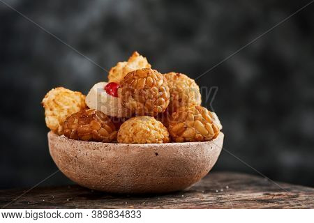 a bowl with some panellets, typical confection of Catalonia, Spain, eaten traditionally in All Saints Day, on a wooden table