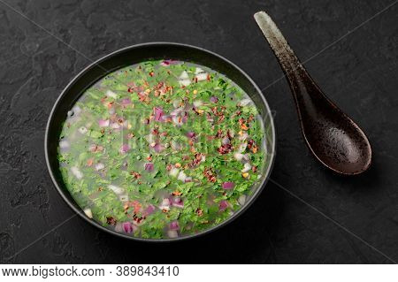 Pachi Pulusu In Black Bowl On Dark Slate Table Top. Raw Tamarind Rasam Is Indian Cuisine Soup Dish.