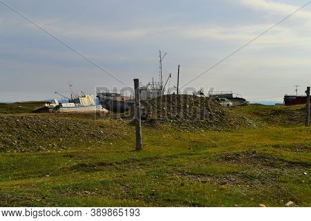 Old Rusty Abandoned Boats, White Ships Lie On Green Grassy Shore In The Light Of The Sunset. Lake Ba