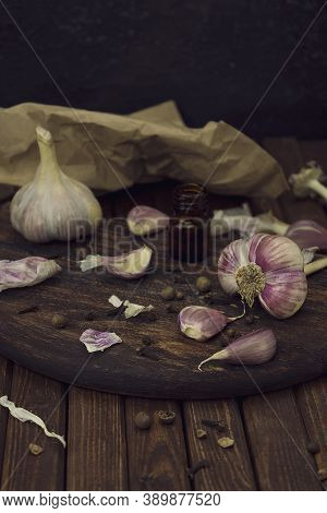 Head And Cloves Of Garlic Are Scattered On A Wooden Cutting Board On A Table Made From Brown Planks