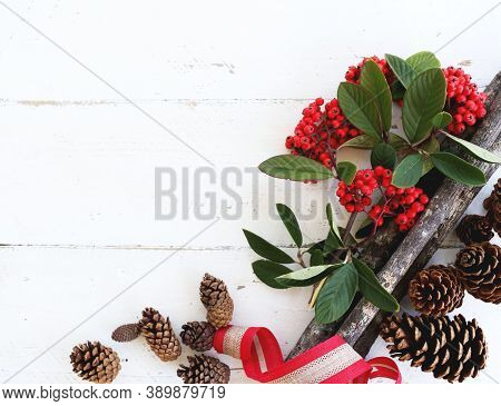 pine cones, cerries and ribbons on wooden planks for Christmas celebrations