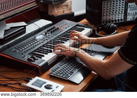 Playing Midi Keyboard. Sound Engineer Working And Mixing Music Indoors In The Studio.