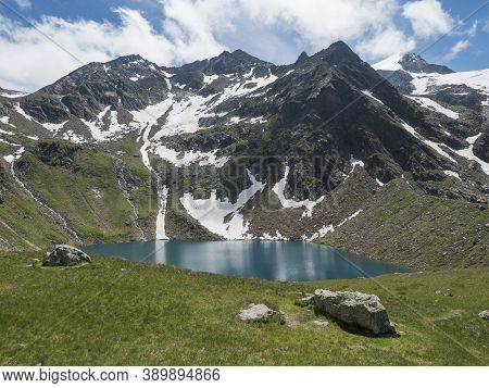 Beautiful Turquoise Blue Mountain Lake Grunausee In Alpine Landscape With Green Meadow And Snow-capp