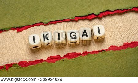 ikigai word abstract in wooden letter cubes against paper abstract, Japanese lifestyle concept  - a reason for being as a balance between love, skills, needs and money