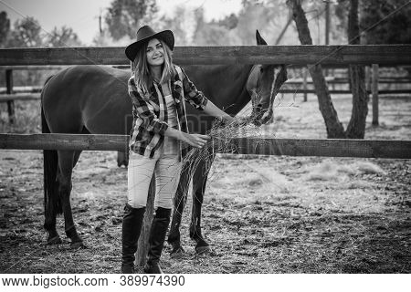 American Woman On A Horse Farm. Portrait Of Girl In Cowboy Hat With A Horses. Hippotherapy At Nature