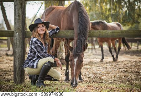 American Woman On A Horse Farm. Portrait Of Girl In Cowboy Hat With A Horses. Hippotherapy At Nature