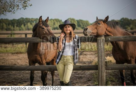 American Woman On A Horse Farm. Portrait Of Girl In Cowboy Hat With A Horses. Hippotherapy At Nature