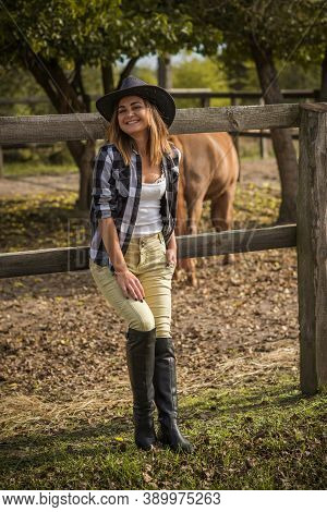 American Woman On A Horse Farm. Portrait Of Girl In Cowboy Hat With A Horses. Hippotherapy At Nature