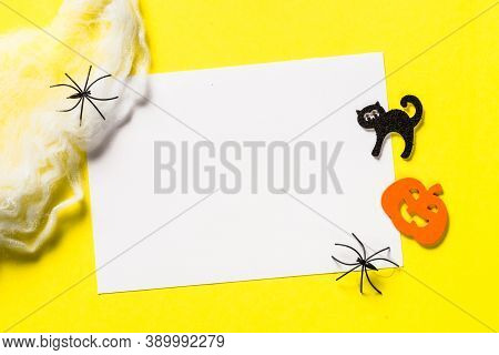 Halloween Flat Lay Composition With Cobweb, Pumpkin, Bat And Place For Taxt At Yellow Background.