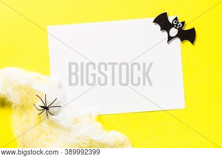 Halloween Flat Lay Composition With Cobweb, Bat And Place For Taxt At Yellow Background.