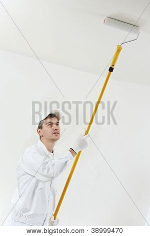 ผู้ปฏิบัติงานชายบ้านจิตรกรหนึ่งจิตรกรรม และปั๊มด้วยลูกกลิ้งทาสี