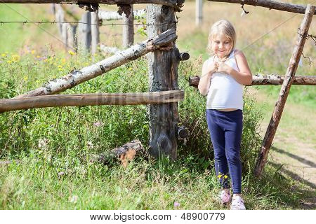 Shy Beautiful Little Girl In White Singlet Standing Close To Fence At Summer. Copyspace