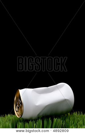 Un'immagine verticale di un bianco schiacciato Can Soda gettato sull'erba verde invece di essere riciclati