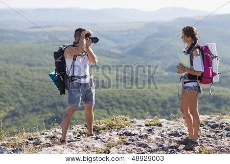 Two Tourists. Man Photographs Woman, She Is Holding A Map.