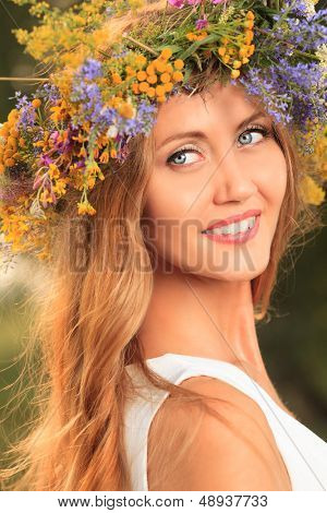 Portræt af en romantisk smilende ung kvinde i en tudorroser af blomster udendørs.