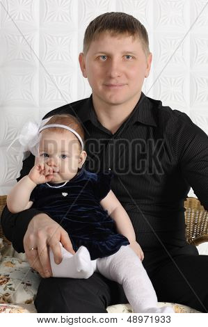 Happy Young Father And His Little Cute Daughter Sit On Wicker Sofa.