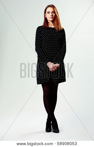 Full-length portrait of a young beautiful woman in casual dress on gray background