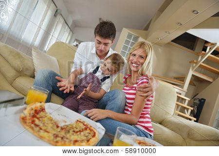 happy young family eating tasty pizza with cheesa and dring healthy and fresh orange juice