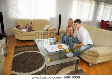 happy young family eating tasty pizza with cheesa and dring healthy and fresh orange juice