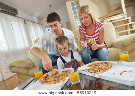 happy young family eating tasty pizza with cheesa and dring healthy and fresh orange juice