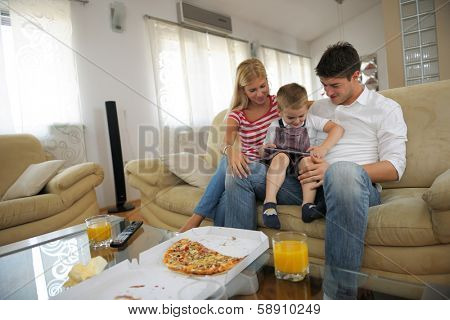 happy young family eating tasty pizza with cheesa and dring healthy and fresh orange juice