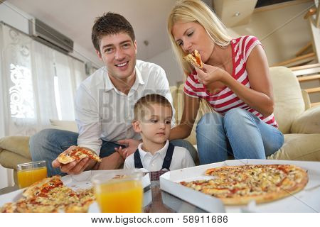 happy young family eating tasty pizza with cheesa and dring healthy and fresh orange juice