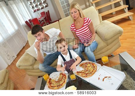 happy young family eating tasty pizza with cheesa and dring healthy and fresh orange juice