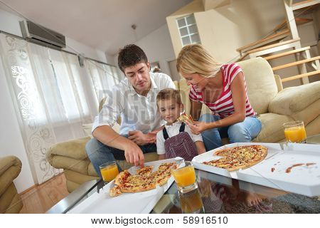 happy young family eating tasty pizza with cheesa and dring healthy and fresh orange juice