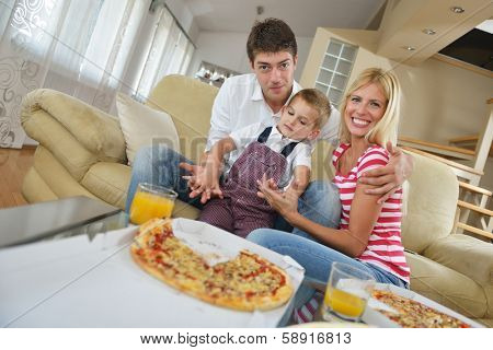 happy young family eating tasty pizza with cheesa and dring healthy and fresh orange juice