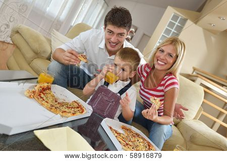 happy young family eating tasty pizza with cheesa and dring healthy and fresh orange juice